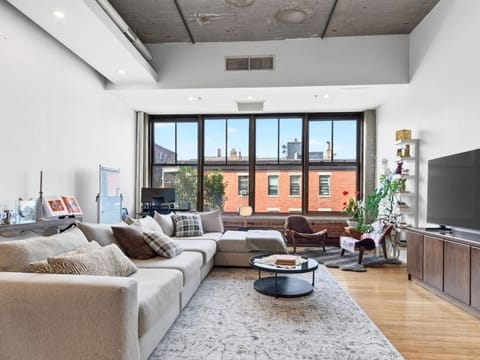 Bright living room with a large sectional sofa and floor-to-ceiling windows