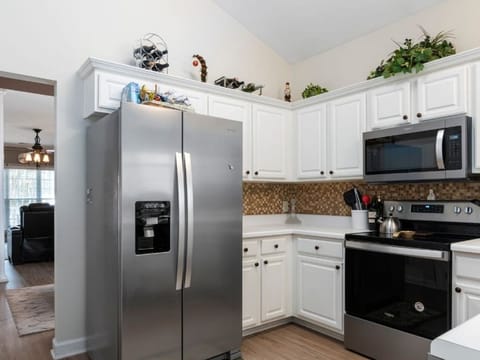 Kitchen with a stainless steel fridge, an oven and white cabinets