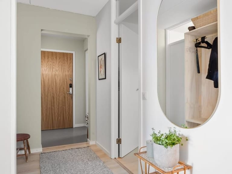 Hallway with a wooden door, a round mirror and a rug