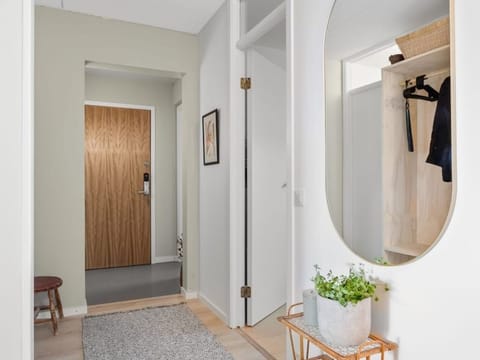 Hallway with a wooden door, a round mirror and a rug